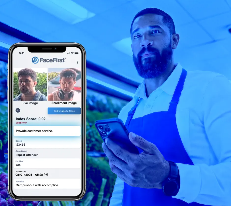A store associate in a blue apron holds his phone beside a FaceFirst mobile alert matching a live image to an enrolled repeat offender.